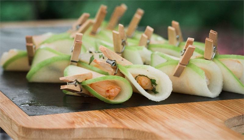 Roulés de concombre garnis, fermés par des pinces en bois, sur ardoise