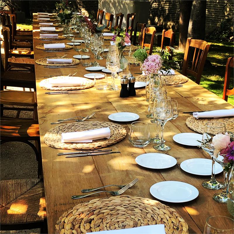 Longue table en bois dressée dans un jardin pour une réception privée